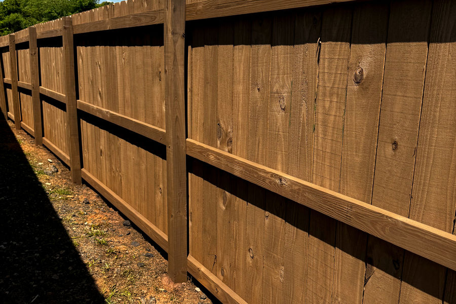 Back side of a privacy fence with rails and posts fully stained