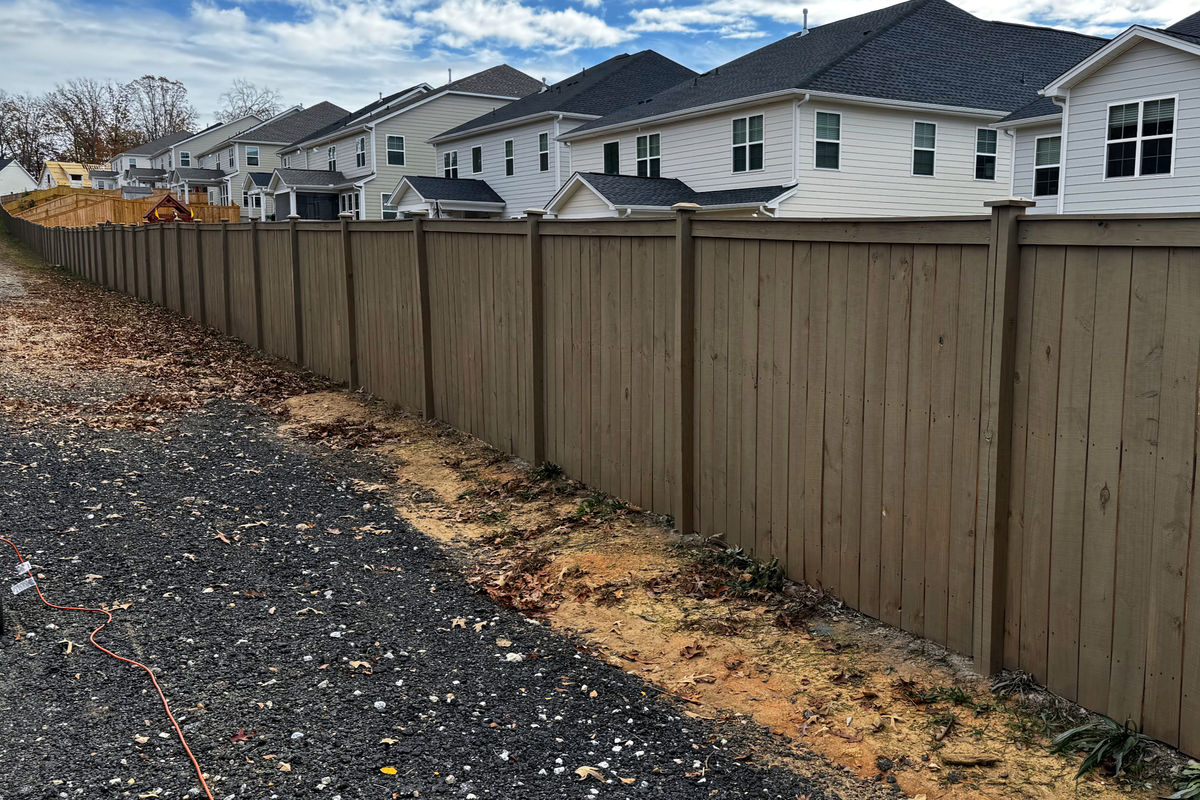 Long oil-stained privacy fence run in a Greenville neighborhood